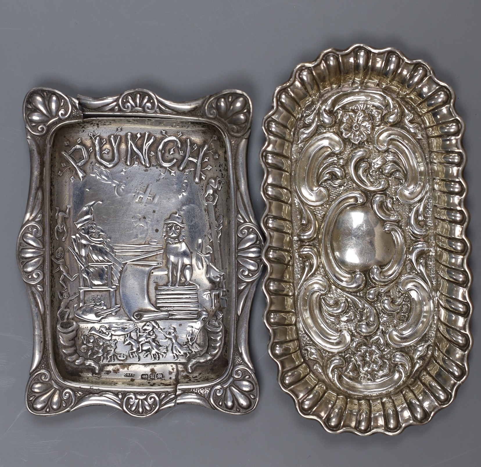 A late Victorian repousse silver 'Mr Punch' pin-tray, 10 x 8cm., Saunders & Shepherd, Birmingham, 1894, 10.7cm, one other silver dish, a silver mounted toilet jar and a plated small dish.